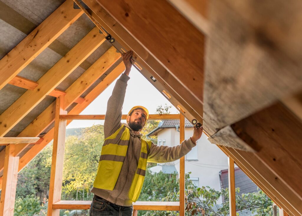 charpentier travaillant la charpente en bois d'une maison traditionnelle par l'intérieur du toit